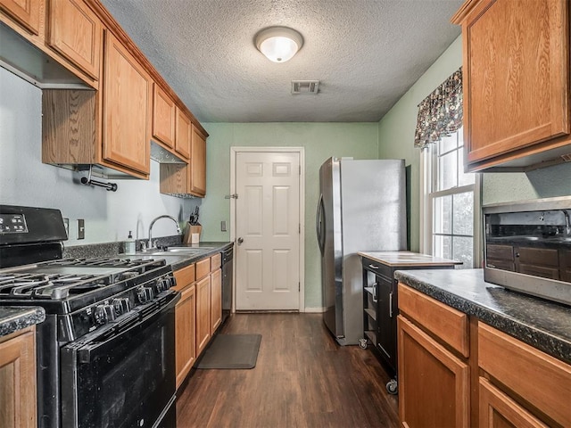 2028 Carlisle Rd, The Village, OK 73120 - kitchen featuring black range with gas cooktop, freestanding refrigerator, dark wood finished floors, dark countertops, and a textured ceiling