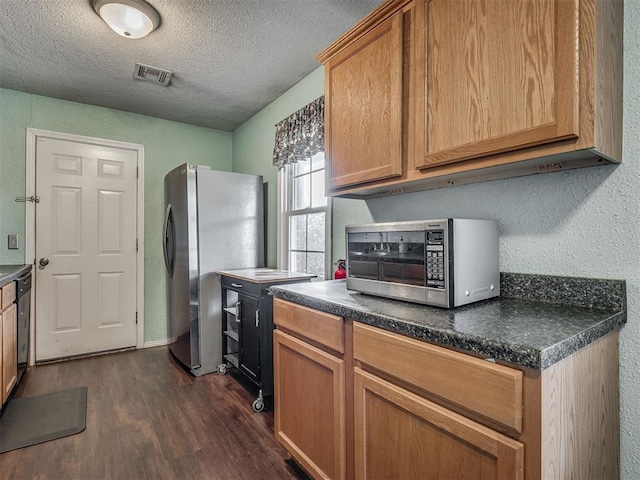 2028 Carlisle Rd, The Village, OK 73120 - kitchen with appliances with stainless steel finishes, dark wood-style flooring, dark countertops, and a textured ceiling