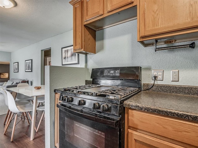 2028 Carlisle Rd, The Village, OK 73120 - kitchen with black range with gas cooktop, dark countertops, dark wood-type flooring, a textured wall, and under cabinet range hood