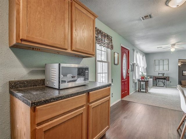 2028 Carlisle Rd, The Village, OK 73120 - kitchen with stainless steel microwave, ceiling fan, dark countertops, dark wood-style floors, and open floor plan