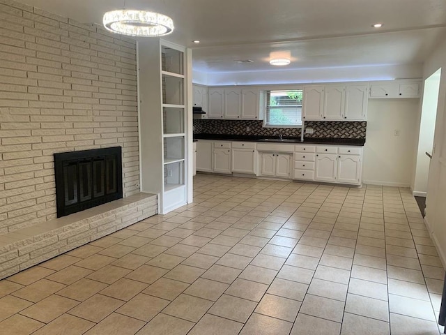 2928 N Downing Ave, Bethany, OK 73008 - kitchen featuring dark countertops, light tile patterned floors, tasteful backsplash, white cabinets, and a brick fireplace