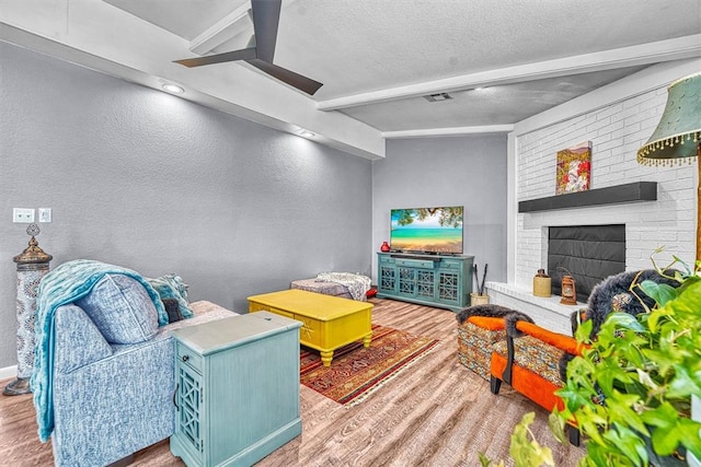 224 N Quail Run, Altus, OK 73521 - living room featuring a textured wall, wood finished floors, beamed ceiling, a textured ceiling, and a ceiling fan