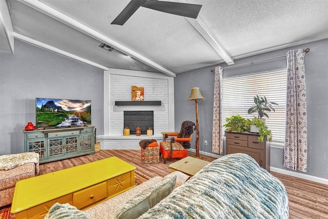 224 N Quail Run, Altus, OK 73521 - living room with a textured ceiling, wood finished floors, ceiling fan, and a brick fireplace