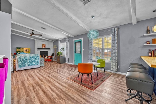 224 N Quail Run, Altus, OK 73521 - dining space with wood finished floors, plenty of natural light, ceiling fan, a fireplace, and a textured ceiling