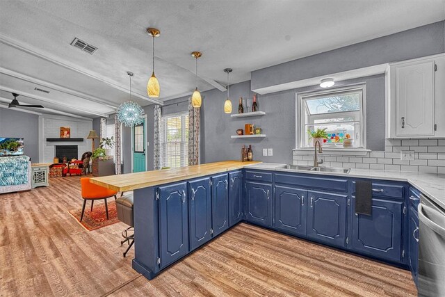 224 N Quail Run, Altus, OK 73521 - kitchen featuring light wood finished floors, stainless steel dishwasher, light countertops, a fireplace, and blue cabinets