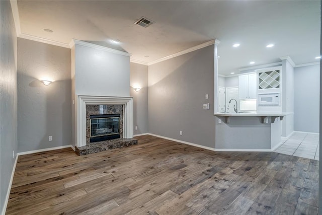 1900 NW 159th Pl, Edmond, OK 73013 - unfurnished living room with ornamental molding, wood finished floors, a high end fireplace, and recessed lighting