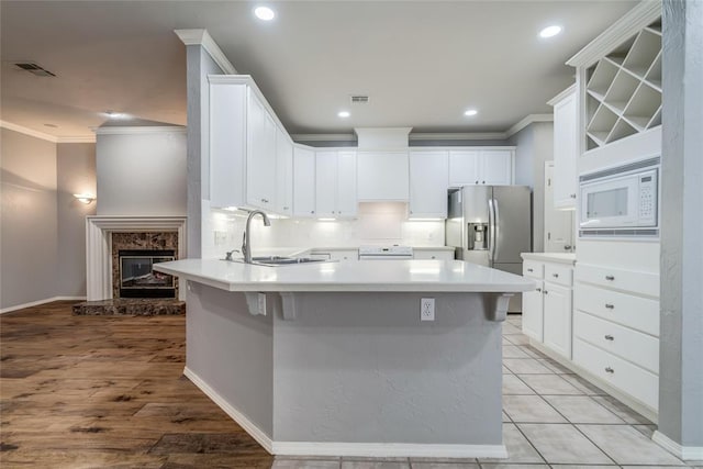 1900 NW 159th Pl, Edmond, OK 73013 - kitchen featuring ornamental molding, a peninsula, stainless steel refrigerator with ice dispenser, white microwave, and backsplash