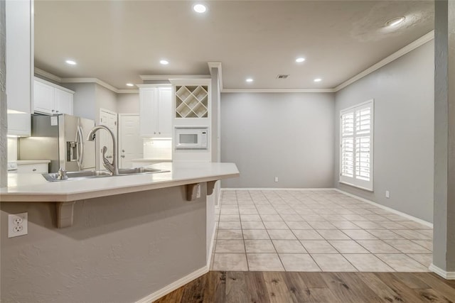 1900 NW 159th Pl, Edmond, OK 73013 - kitchen with stainless steel fridge with ice dispenser, crown molding, white microwave, a peninsula, and a kitchen breakfast bar