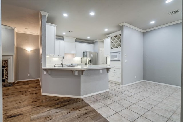 1900 NW 159th Pl, Edmond, OK 73013 - kitchen with stainless steel refrigerator with ice dispenser, white microwave, crown molding, a peninsula, and a breakfast bar