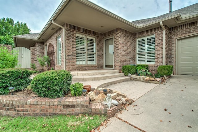 1900 NW 159th Pl, Edmond, OK 73013 - view of exterior entry with brick siding, concrete driveway, a garage, and roof with shingles