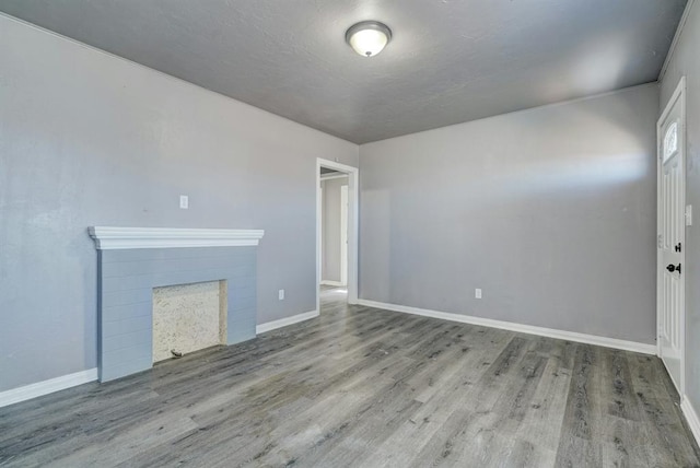 2132 N Rhode Island Ave, Oklahoma City, OK 73111 - unfurnished living room featuring wood finished floors, a fireplace, and a textured ceiling