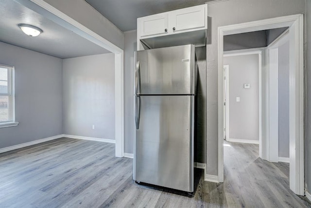 2132 N Rhode Island Ave, Oklahoma City, OK 73111 - kitchen with freestanding refrigerator, light wood finished floors, and white cabinets