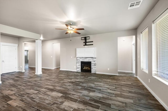 2020 Sara Vista Dr, Yukon, OK 73099 - unfurnished living room with a ceiling fan, dark wood finished floors, a stone fireplace, and decorative columns