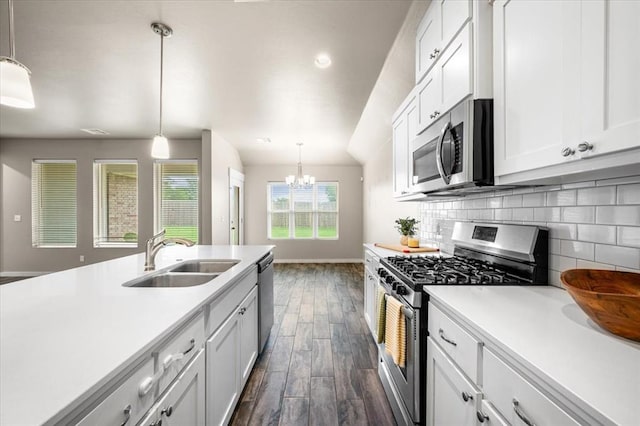 2020 Sara Vista Dr, Yukon, OK 73099 - kitchen featuring appliances with stainless steel finishes, dark wood-style floors, a chandelier, light countertops, and backsplash