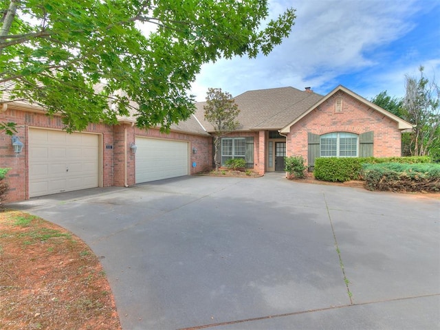 112 Lakeview Ct, Edmond, OK 73003 - view of front of home with brick siding, concrete driveway, a garage, and roof with shingles