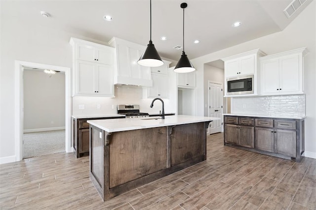 10400 SW 51st St, Mustang, OK 73064 - kitchen with stainless steel appliances, light wood-type flooring, decorative backsplash, a center island with sink, and light countertops