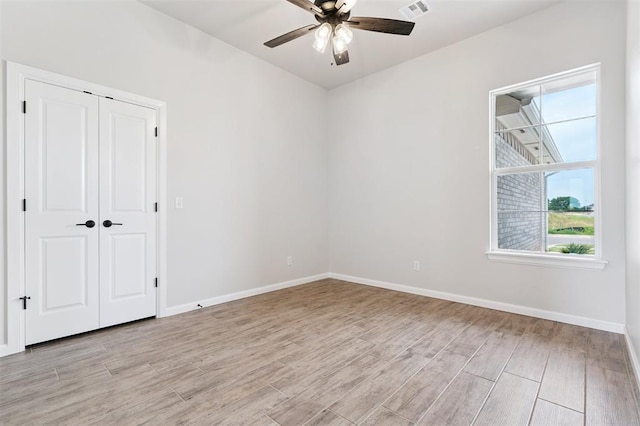 10400 SW 51st St, Mustang, OK 73064 - unfurnished bedroom with light wood-style flooring, multiple windows, ceiling fan, and a closet