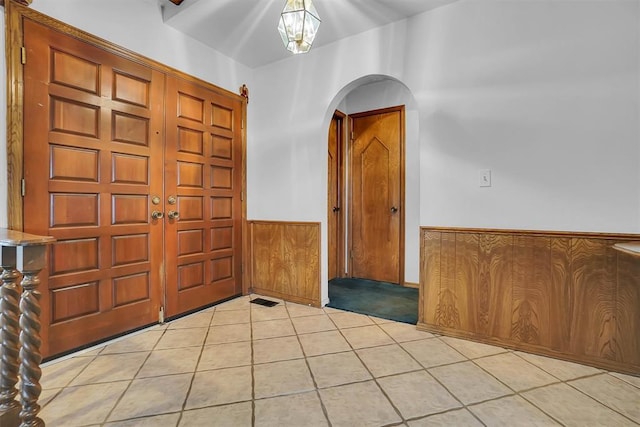 813 Tottingham Rd, Anadarko, OK 73005 - foyer entrance with arched walkways, wainscoting, light tile patterned floors, and wood walls