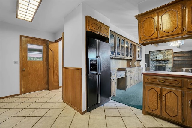 813 Tottingham Rd, Anadarko, OK 73005 - kitchen featuring black fridge with ice dispenser, light tile patterned floors, wainscoting, glass insert cabinets, and brown cabinetry