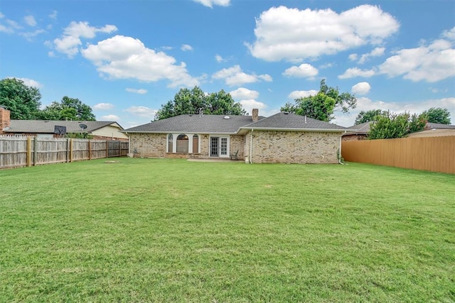 813 Tottingham Rd, Anadarko, OK 73005 - back of property featuring a fenced backyard, french doors, a chimney, and brick siding