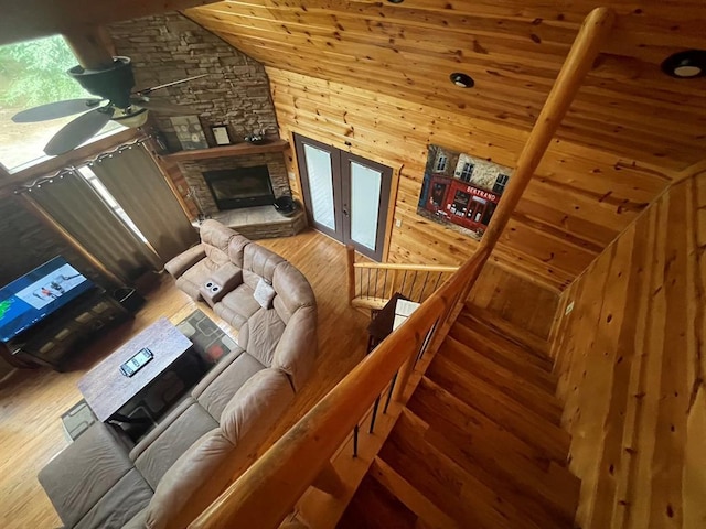 113 Bentwater Rd, Broken Bow, OK 74728 - living area featuring wood finished floors, a ceiling fan, lofted ceiling, wooden walls, and a stone fireplace