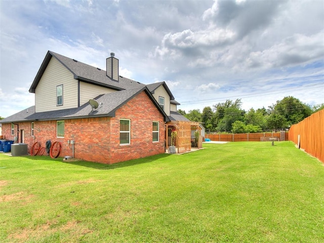 11712 Muirfield Ln, Guthrie, OK 73044 - back of house featuring brick siding, a fenced backyard, a chimney, and roof with shingles
