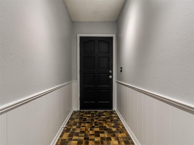 201 S Patterson Dr, Moore, OK 73160 - doorway featuring a wainscoted wall, a decorative wall, and a textured ceiling