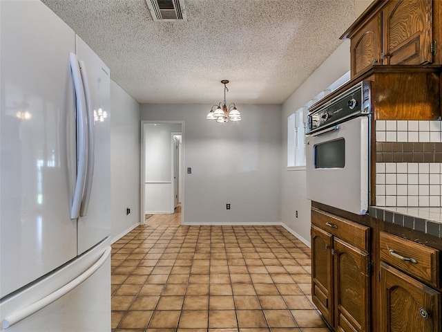 201 S Patterson Dr, Moore, OK 73160 - kitchen with white appliances, dark countertops, a chandelier, a textured ceiling, and pendant lighting