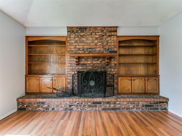 201 S Patterson Dr, Moore, OK 73160 - unfurnished living room featuring wood finished floors, a textured ceiling, and a brick fireplace