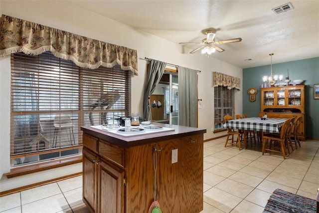 1748 Logans Run, Chandler, OK 74834 - kitchen with light tile patterned floors, a chandelier, a ceiling fan, brown cabinetry, and white cooktop