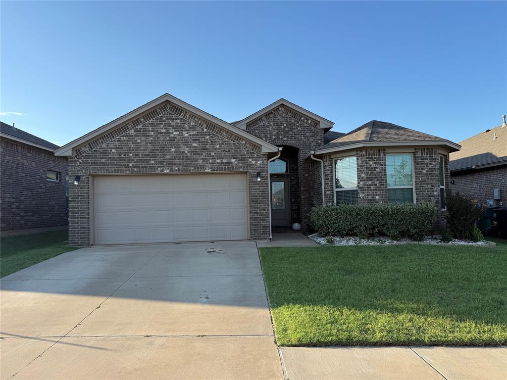 11325 SW 33rd Ter, Yukon, OK 73099 - view of front facade featuring brick siding, a front yard, driveway, and an attached garage