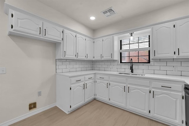 1712 N 4th St, Sayre, OK 73662 - kitchen with light wood-style floors, decorative backsplash, white cabinetry, and light countertops