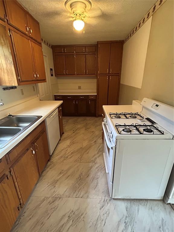 1708 W Modelle Ave, Clinton, OK 73601 - kitchen featuring white appliances, a textured ceiling, light countertops, brown cabinetry, and ceiling fan