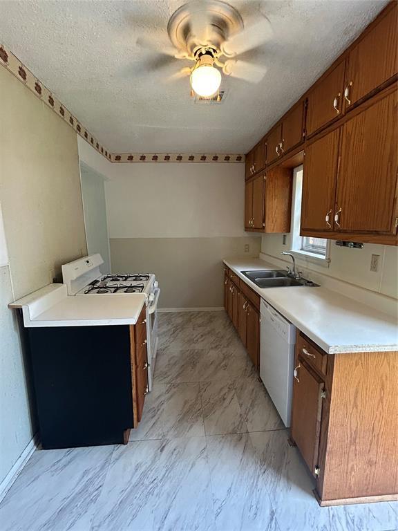 1708 W Modelle Ave, Clinton, OK 73601 - kitchen featuring white appliances, light countertops, a ceiling fan, brown cabinets, and a textured ceiling