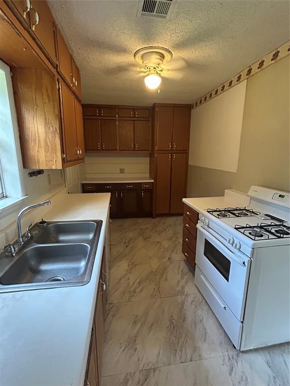 1708 W Modelle Ave, Clinton, OK 73601 - kitchen with white range with gas cooktop, a textured ceiling, light countertops, and light marble finish floors