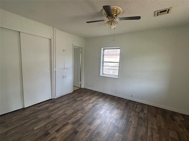 1708 W Modelle Ave, Clinton, OK 73601 - unfurnished bedroom featuring dark wood-type flooring, a textured ceiling, a closet, and a ceiling fan