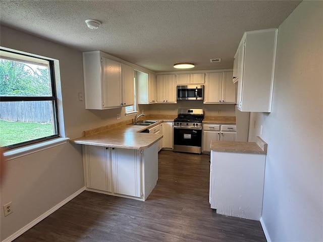 1213 Dreessen Dr, Moore, OK 73160 - kitchen featuring stainless steel appliances, dark wood finished floors, light countertops, a textured ceiling, and a peninsula