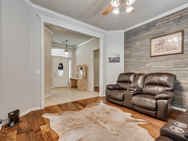 1810 Sandpiper Dr, Blanchard, OK 73010 - living room featuring an accent wall, a ceiling fan, wooden walls, crown molding, and wood finished floors