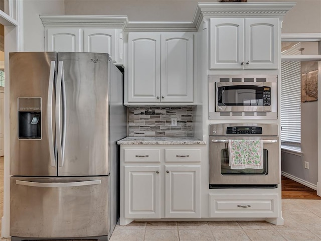 1810 Sandpiper Dr, Blanchard, OK 73010 - kitchen with appliances with stainless steel finishes, light stone countertops, light tile patterned floors, tasteful backsplash, and white cabinetry