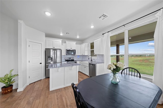 2326 County Road 1335, Blanchard, OK 73010 - kitchen with stainless steel appliances, a center island, white cabinets, backsplash, and light stone countertops