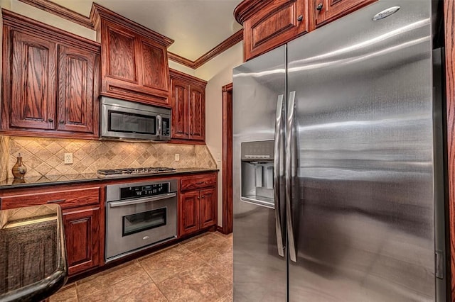 1865 Buckskin Ct, Blanchard, OK 73010 - kitchen featuring appliances with stainless steel finishes, dark countertops, decorative backsplash, tile patterned flooring, and crown molding