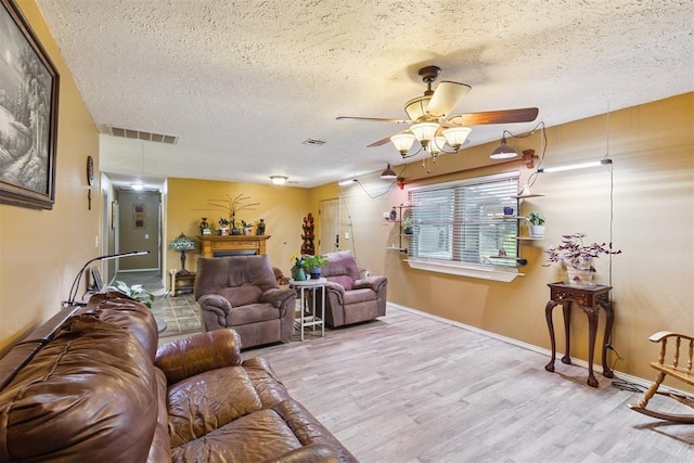 349760 E 970th Rd, Sparks, OK 74869 - living room with a textured ceiling, ceiling fan, wood finished floors, and a fireplace