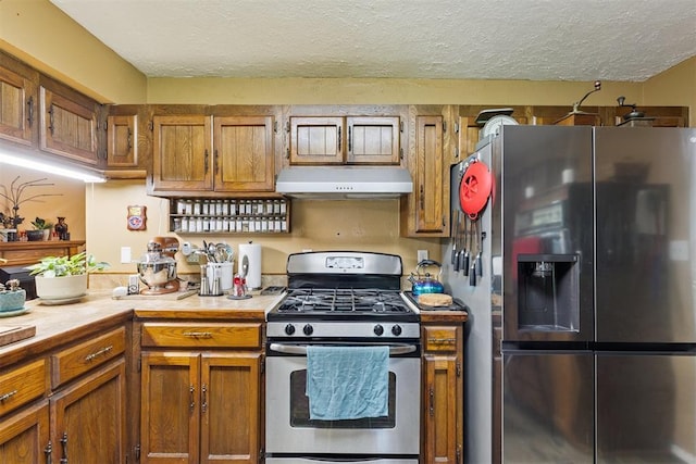349760 E 970th Rd, Sparks, OK 74869 - kitchen featuring appliances with stainless steel finishes, under cabinet range hood, brown cabinetry, a textured ceiling, and light countertops
