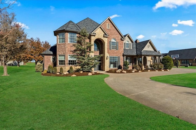 108 E Stroh Ave, Okarche, OK 73762 - view of front of home featuring stone siding, a front lawn, curved driveway, brick siding, and a chimney