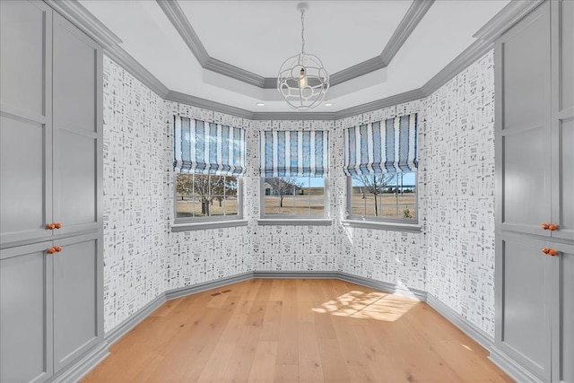 108 E Stroh Ave, Okarche, OK 73762 - unfurnished dining area with a chandelier, wallpapered walls, ornamental molding, light wood-style flooring, and a raised ceiling