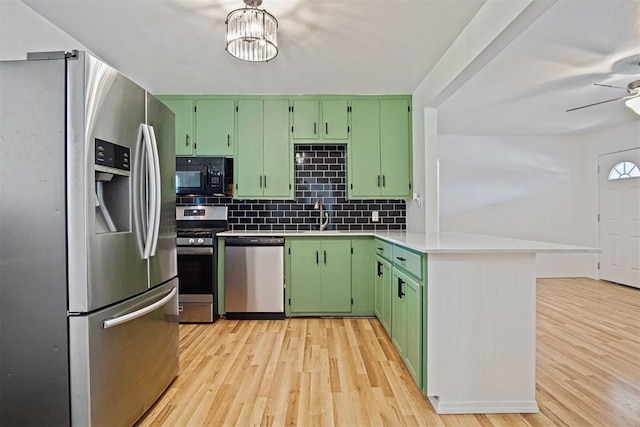 312 Jon St, Guthrie, OK 73044 - kitchen featuring appliances with stainless steel finishes, green cabinetry, light wood-style floors, and tasteful backsplash