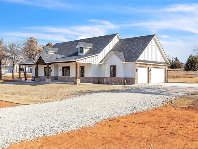 1092 S Mustang Rd, Blanchard, OK 73010 - modern inspired farmhouse with gravel driveway, a porch, board and batten siding, a shingled roof, and an attached garage