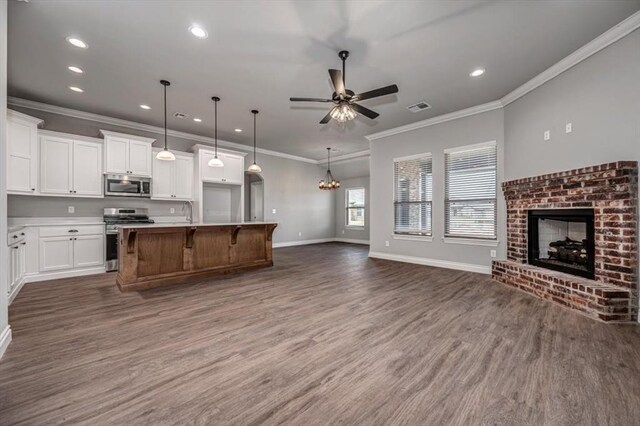 2013 W Crossbow Way, Mustang, OK 73064 - kitchen with appliances with stainless steel finishes, open floor plan, a fireplace, dark wood-style floors, and recessed lighting