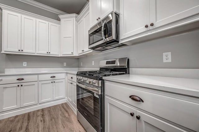 2013 W Crossbow Way, Mustang, OK 73064 - kitchen with appliances with stainless steel finishes, light countertops, light wood-style flooring, white cabinets, and ornamental molding