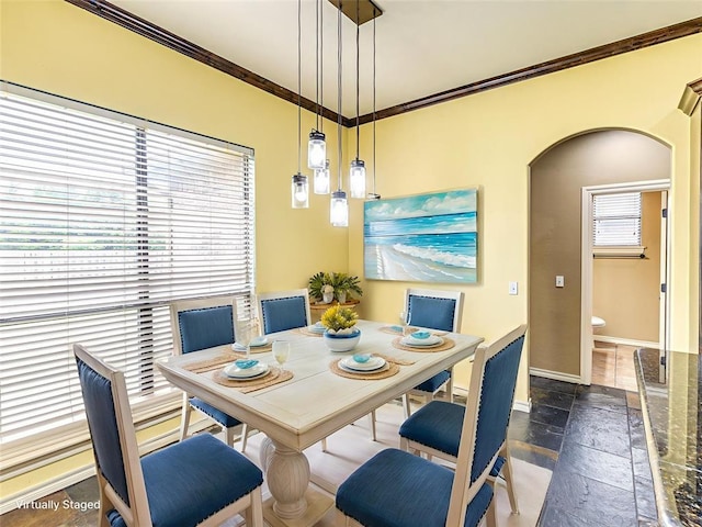 2311 Washita Trl, Edmond, OK 73003 - dining space featuring stone tile floors, crown molding, and arched walkways